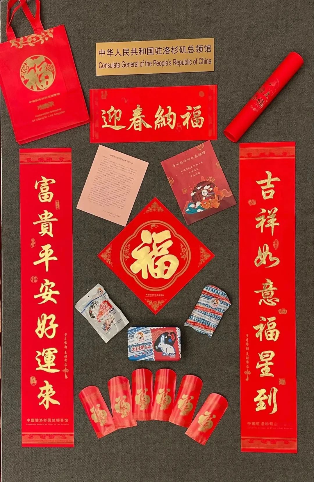 A display of Chinese New Year gifts from the Consulate General of China in Los Angeles, including Fu characters, couplets, red envelopes, and candy.
