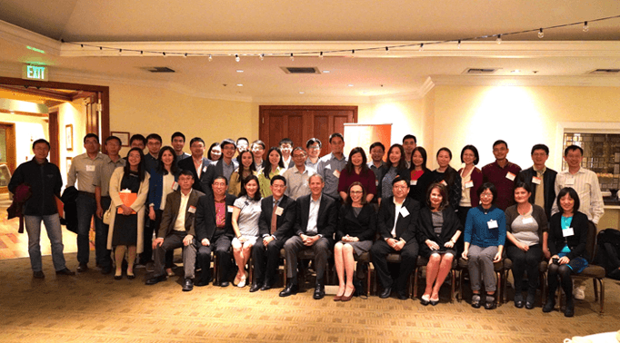A large group of people, mostly Asian, posing for a photo indoors. Some are standing, others are seated in the front row.