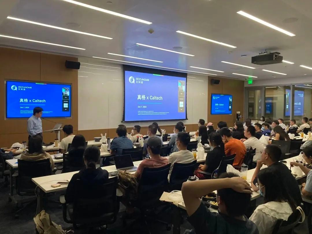 A speaker presents to an audience in a room with multiple screens displaying "ACCUNOME" and "真格 x Caltech".